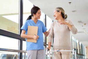 Caregiver reviews a medication chart with an older resident at a dining table.