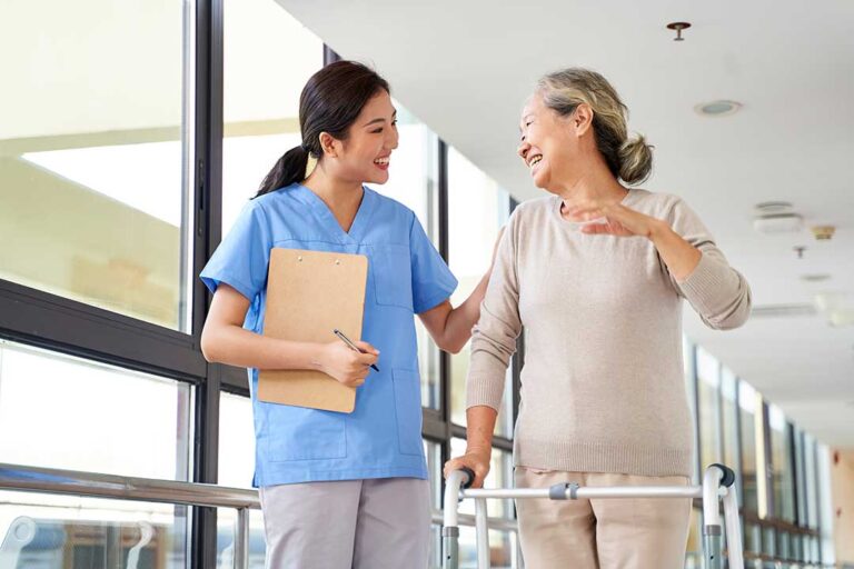 Caregiver reviews a medication chart with an older resident at a dining table.