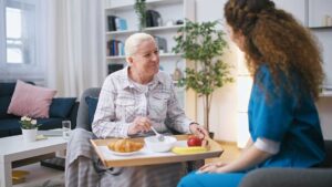 Older adults perform seated and standing exercises with resistance bands in a bright assisted living activity room.