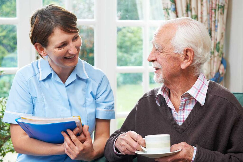 Residents practice gentle chair stretches with a facilitator in a bright assisted living activity room.